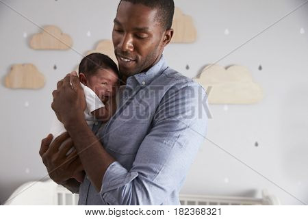 Father Holding Newborn Baby Son In Nursery