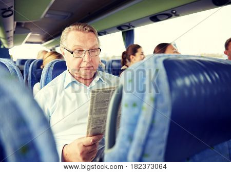 transport, tourism, trip and people concept - senior man reading newspaper in travel bus