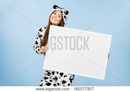 Smiling teenage girl in funny nightclothes pajamas cartoon style with blank empty banner board. Advertisement copyspace.