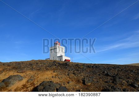Vik Iceland's Dyrholaey Lighthouse against a blue sky.