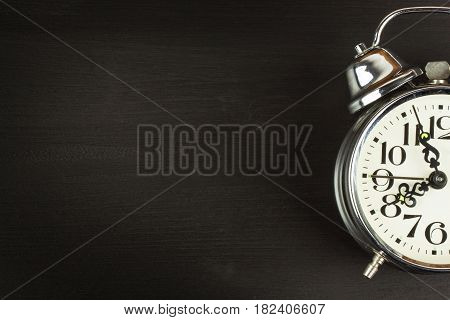 Retro metal alarm clock on a black wooden background. Open your eyes. Reveille to wake up. Place for text