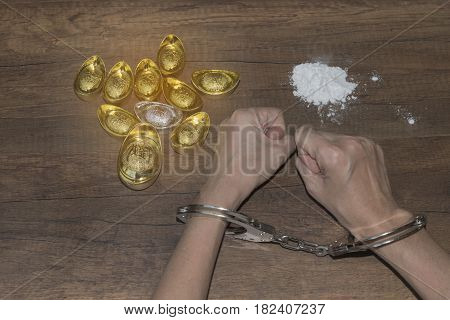 The chrome metal handcuffed bondage on man hand during holding gold bar represent the crime fraud and punishment equipment concept related idea. Addictive substance no freedom Translation in English meaning lucky and richly