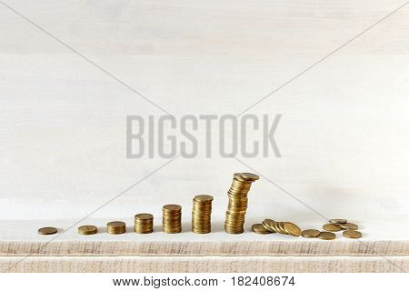 Growing coins columns, the biggest one is falling, all on wooden background. Do not keep all your eggs in one basket