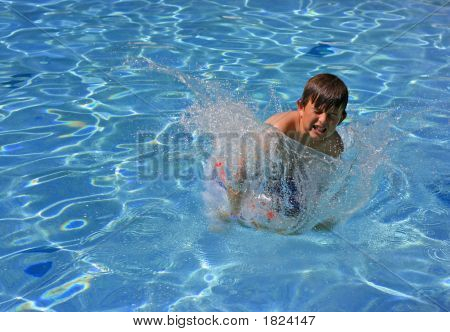 Ein kleiner Junge, springen und in einen Pool plantschen
