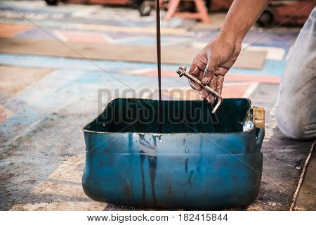 Close up of Used engine oil in a Plastic canisters with mechanic hand at the garage.
