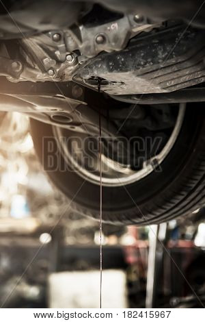Close up of eninge oil at below of a car. Changing motor oil at the garage.