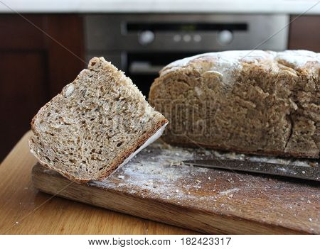 Bread lof with a cut piece in the kitchen. Homemade rye bread cut into pieces on the wooden board.