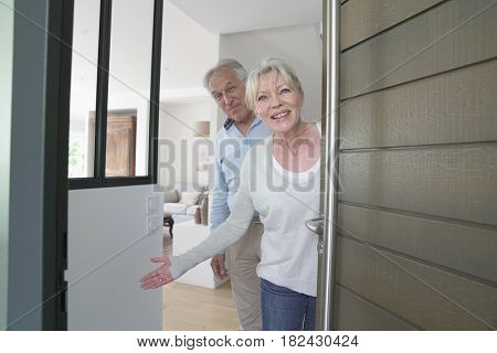 Senior people welcoming friends to enter home