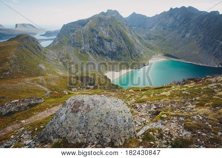 Beautiful Vibrant Norwegian Mountain Landscape from Ryten peak - famous mountain in Lofoten Islands, Moskenes municipality, Nordland with a view of Kvalvika beach, with hiking tourists and blue sky