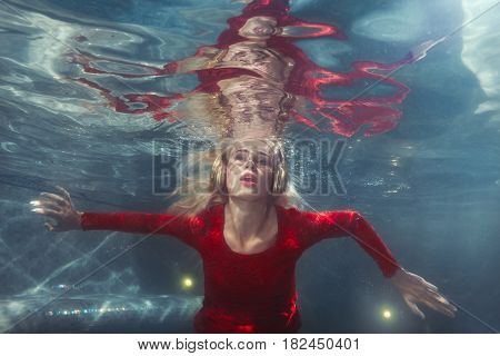 Woman listens to music under the water in the pool.