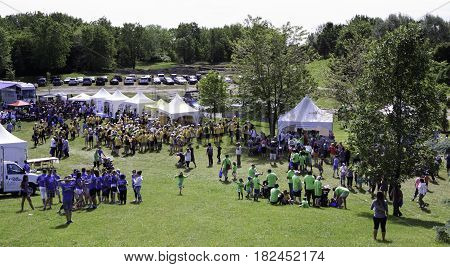 Laval, Quebec - June 14, 2015 - Landscape view of the large crowd of people in colorful t-shirts checking out the event tents attractions at the 
