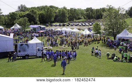 Laval, Quebec - June 14, 2015 - Landscape view of the large crowd of people in colorful t-shirts checking out the event tents attractions at the 