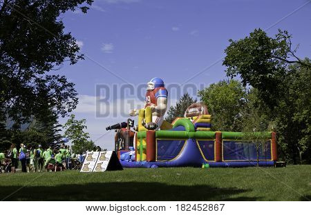Laval, Quebec - June 14, 2015 - Landscape view of a large football themed blow up play equipment with a group of people waiting to jump inside at the 
