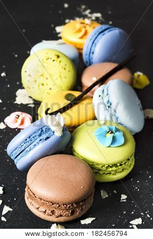 Assorted colorful french cookies macaroons on a black background. Space for text. Closeup. Top view. Concept of the baking macaroons