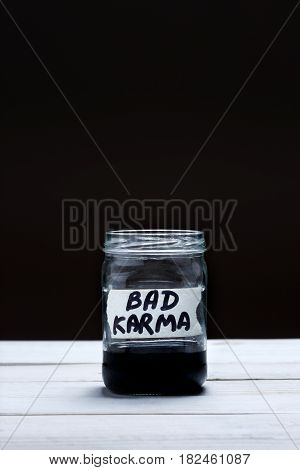 Bad Karma - an inscription on the label of a glass jar with a liquid of black color on a black and white background