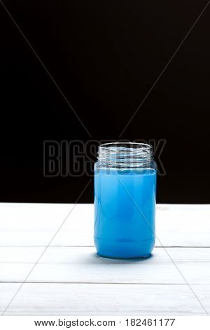 Glass jar with a liquid of blue color on black and white background