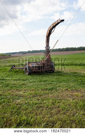 Old rusty mower on the newly mown grass in the field. Agricultural machinery.