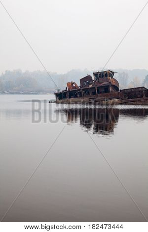 Old rusty sunken ship in water in a foggy day.