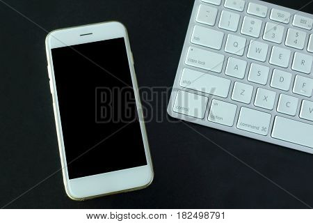 Hand holding mockup smartphone with keyboard on black background