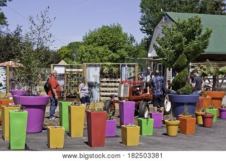 Laval, Quebec - June 14, 2015 - Wide view of people checking out a red tractor in the very colorful Garden Center of the Nature Park, Laval, Quebec on a sunny day in June.