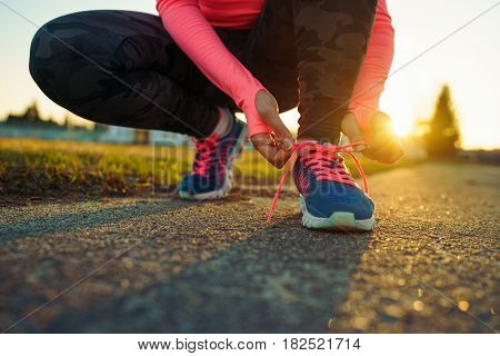Running shoes - woman tying shoe laces. Closeup of female sport fitness runner getting ready for jogging outdoors