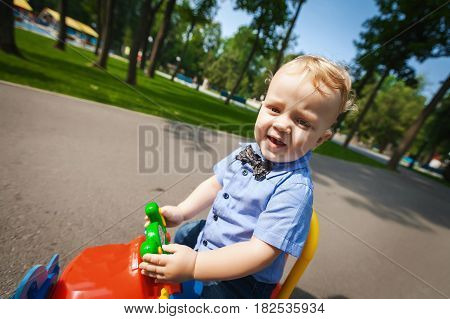 Little cute blond kid boy driving color toy plane and having fun outdoors. Child enjoying warm summer day in nature landscape