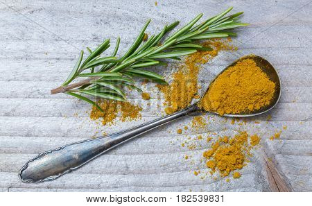 Curry powder and rosemary on a spoon macro.