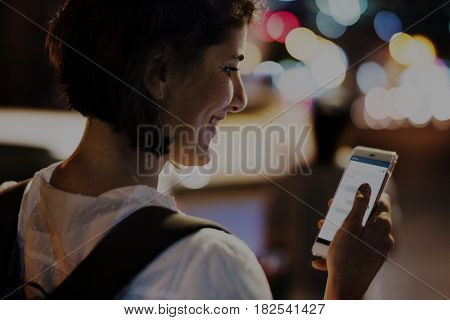 Woman using smart phone walking on street night time