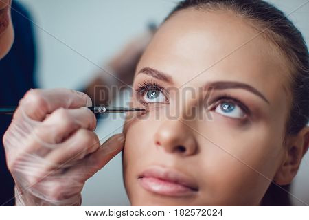 Professional make-up artist makes eye makeup of model. Beauty and fashion concept. Close up.