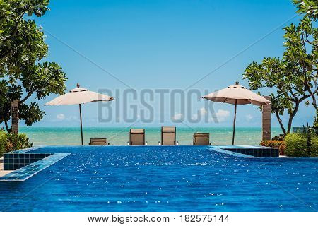 Tropical beach resort with lounge chairs and umbrella with the sea and blue sky background Cha-am - Hua Hin Thailand