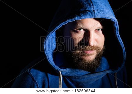 Solid bearded middle-aged man in a hood  portrait on black background