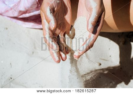Sand running through hands on beach background