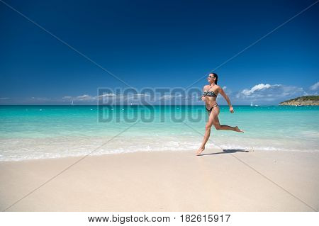 woman with beautiful body in swimsuit running in ocean water sunny day at tropicl beach sport and wellness concept