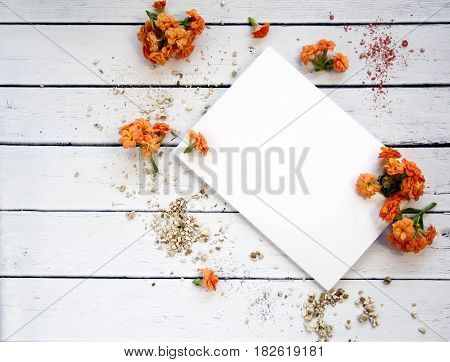 White sheet of paper with space for text with orange flowers and gold powder. Top view. Female desktop. Rustic white table. A gentle romantic style.