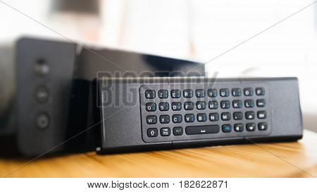 Full keyboard on small remote control next to wireless tv box used for TV Internet Telephone communication via fiber optic or coaxial cable
