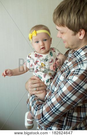 Beautiful happy smiling daddy of European appearance holds on the hands of a little baby girl
