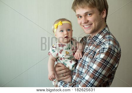 Beautiful happy smiling daddy of European appearance holds on the hands of a little baby girl