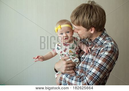 Beautiful happy smiling daddy of European appearance holds on the hands of a little baby girl