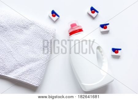 laundry set with pastel towels and detergent plastic bottel on white table background top view