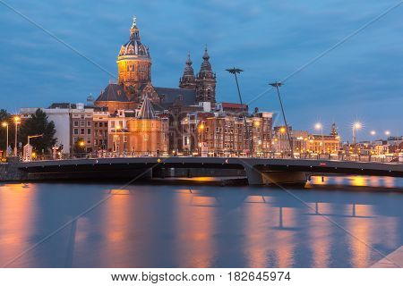 Night city view of Amsterdam canal, bridge and Basilica of Saint Nicholas, Holland, Netherlands. Long exposure