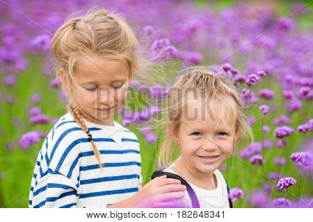 Little adorable girls walking outdoor with flowers