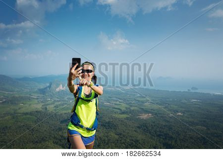 successful woman hiker taking photo with cellphone hiking on mountain peak
