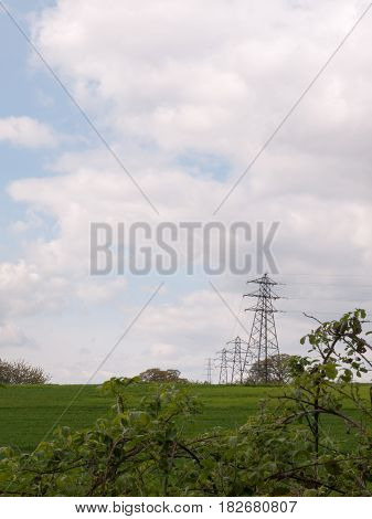 A Shot Of Far Away Field Green And With Several Lined Up Electrical Wire Metal Frames Standing And W