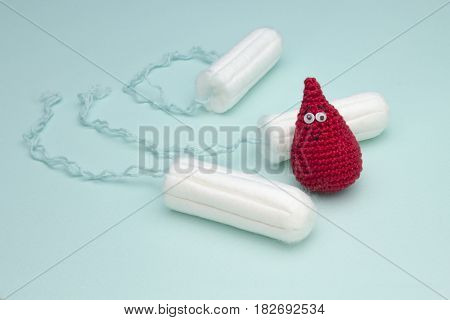 Three menstruation sanitary soft cotton tampons for woman hygiene protection and crochet funny blood drop. Woman critical days gynecological menstruation cycle. Medical conception photo
