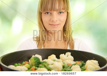 Image of a young woman cooking healthy food,against abstract green background