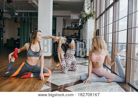 Young attractive women practicing yoga on the floor near window at the gum