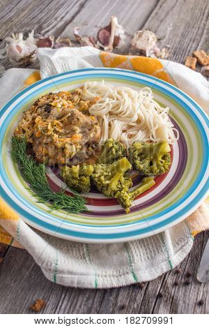 Pasta with chicken and vegetables on a dark wood in a rustic style