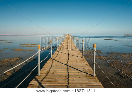 Pier in the Red sea in resort. Summer vacation on Red sea. View at a clear sea with turquoise water in windless conditions. Summer vacation at a sea coastline in an exotic country.