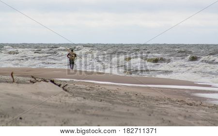 Lonely man on the beach. Amber gathering stormy weather.