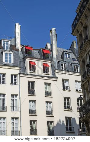 Red sun awnings on the windows of the attic. Paris France.